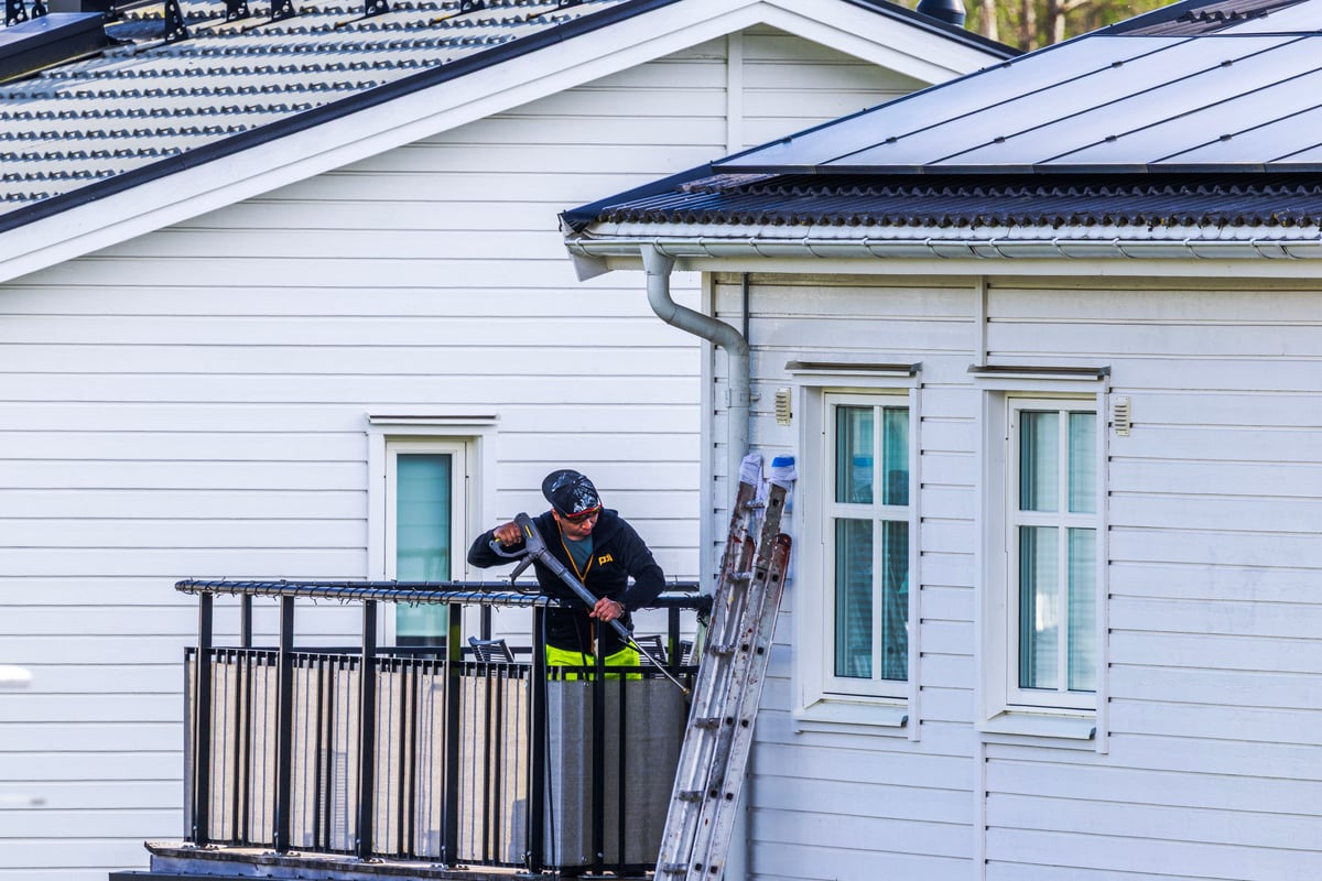 Worker cleaning a home facade gently as part of a professional soft washing service